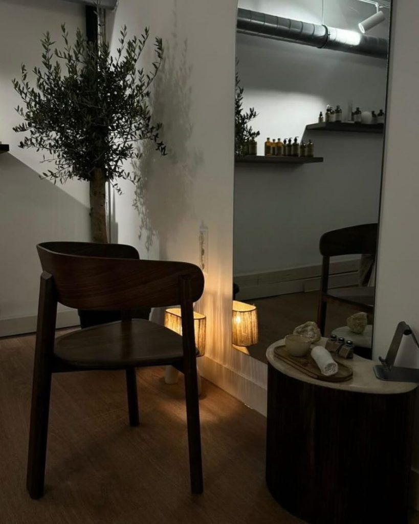 Interieur van Curly Head Spa met een houten stoel, grote spiegel en sfeerverlichting.